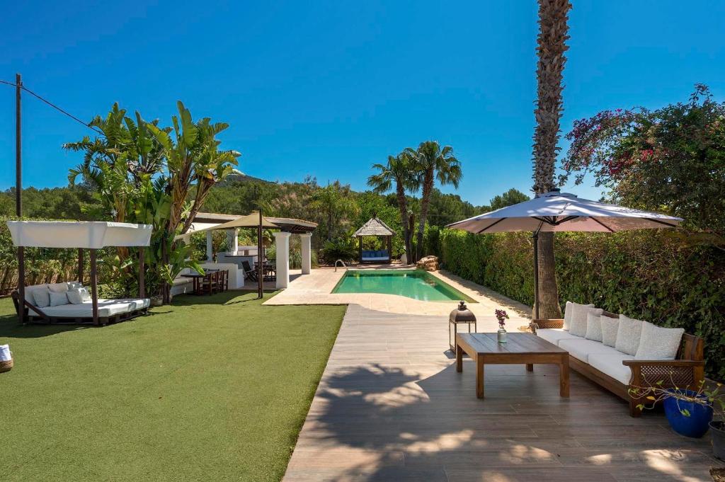 a backyard with a swimming pool and an umbrella at Can Botanic in Sant Josep de sa Talaia