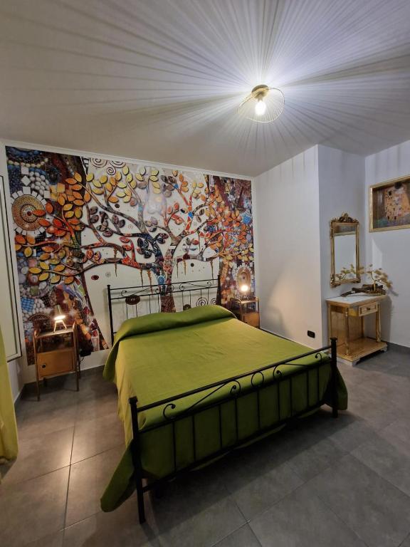 a bedroom with a green bed and a painting on the wall at L'Alloggio dell'Artista in Belpasso