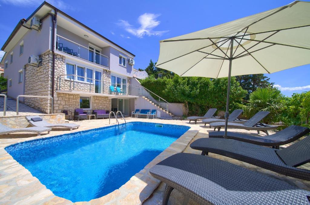 a pool with chairs and an umbrella next to a house at Villa Vinodol *with great sea view and pool in Novi Vinodolski