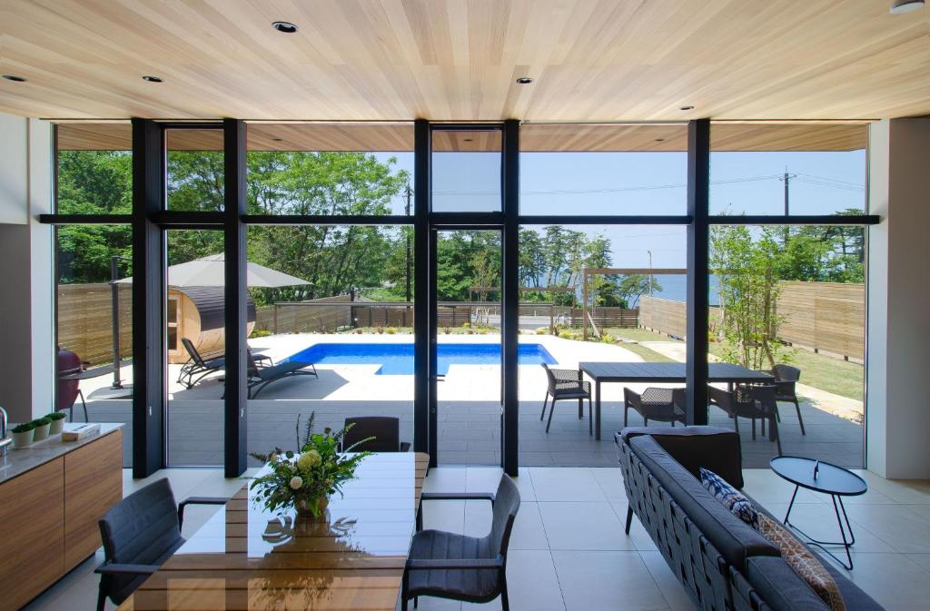 a living room with glass walls and a pool at Morris Resort Tohginbow in Sakai