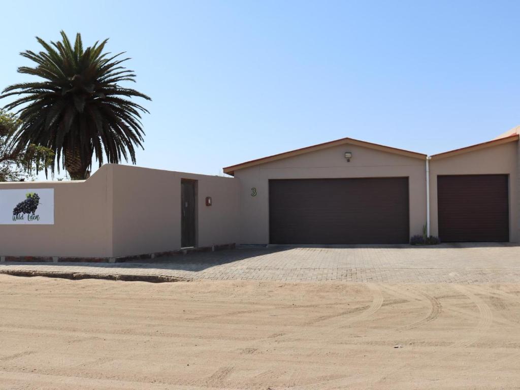 a house with two garage doors and a palm tree at Wild Eden Self-Catering Accommodation in Swakopmund