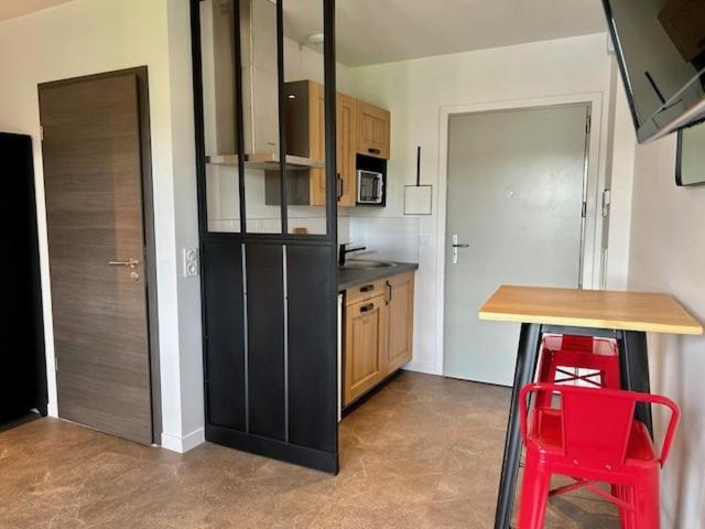 Il comprend une cuisine équipée d'un réfrigérateur noir et d'une table en bois. dans l'établissement Appartement contemporain, à Stiring-Wendel