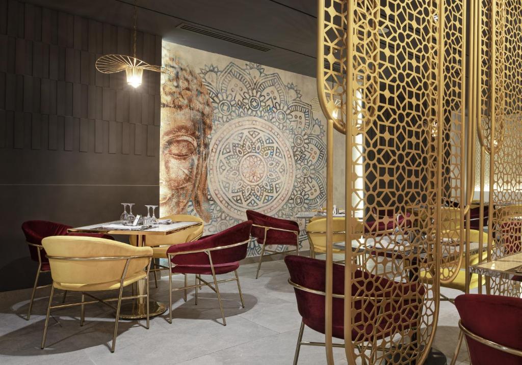 a restaurant with tables and chairs and a wall with a mural at V Hotel Sharm El Shiekh in Sharm El Sheikh