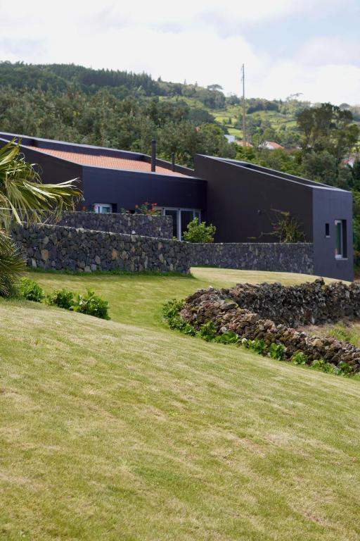 a house with a stone wall and a yard at Casas da Prainha C in Canto da Areia