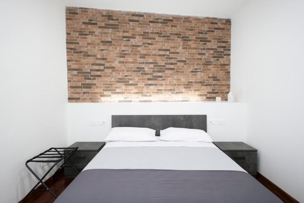 a bed in a room with a brick wall at Napoli Factory Guest House in Naples