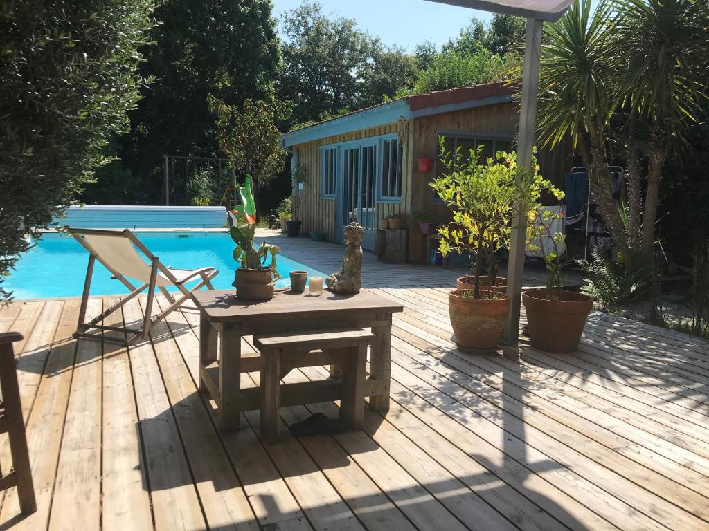 une terrasse en bois avec une table à côté de la piscine dans l'établissement Villa Piscine, à Gujan-Mestras