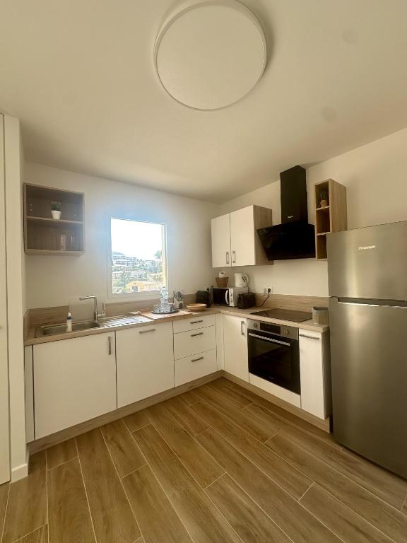 une cuisine avec des armoires blanches et un réfrigérateur en acier inoxydable dans l'établissement Beau 2 pièces neuf 3 personnes, à LʼÎle-Rousse