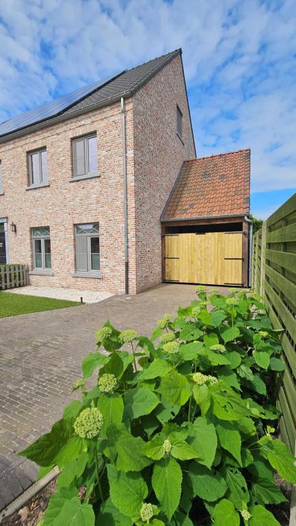 a brick house with a wooden garage at Vakantiehuis Pippa in Peer