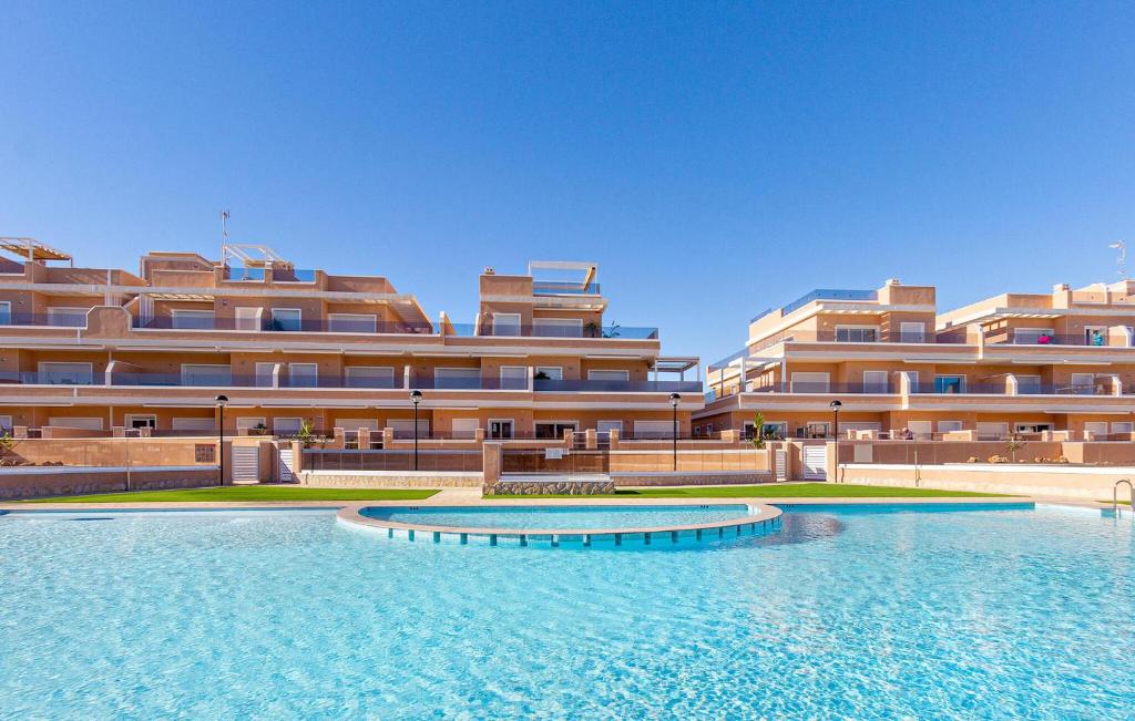 Un gran edificio con una piscina en frente. en Cozy Apartment In Torre De La Horadada, en Torre de la Horadada