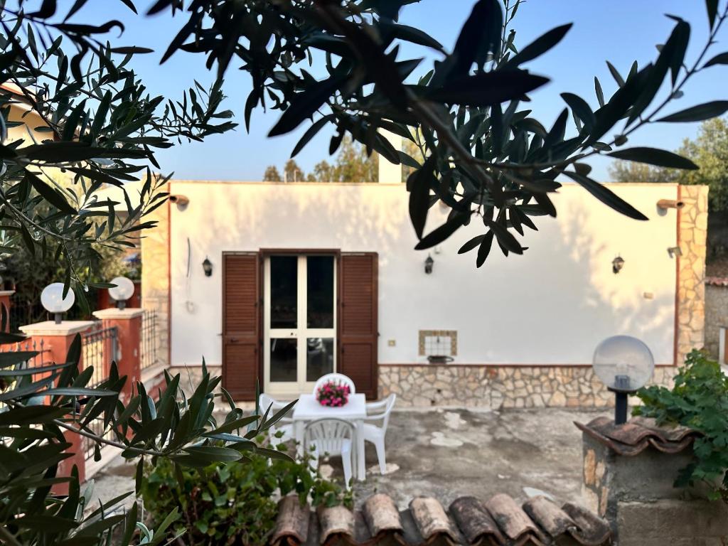 a patio with a white table and chairs in front of a house at La Dimora degli ulivi in Tusa