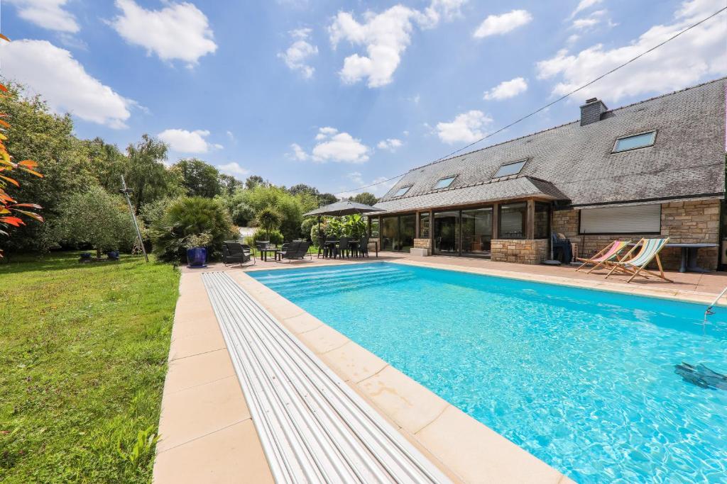 une image d'une piscine en face d'une maison dans l'établissement Sarzeau - 12 pers - Piscine couverte et Billard, à Sarzeau