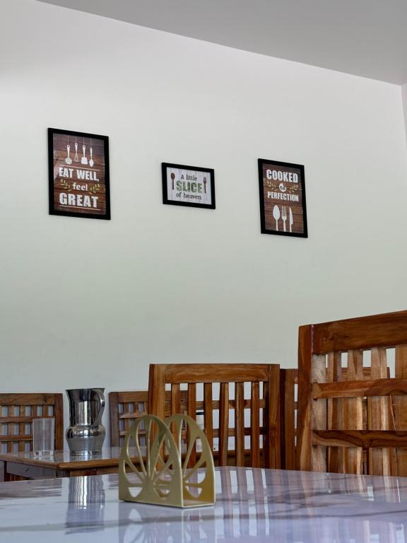 a dining room with a table and chairs and three signs at Hotel Kalyani in Nandaprayāg