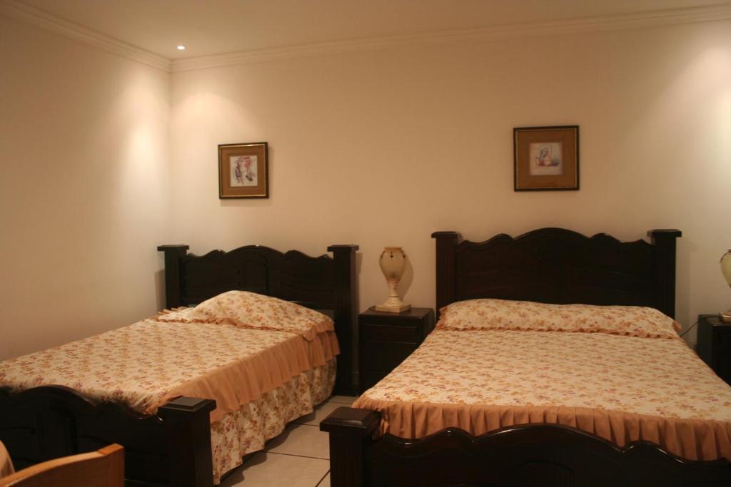 een slaapkamer met twee bedden en twee foto's aan de muur bij Hotel y Restaurante Costa del Sol in Mata de Limón