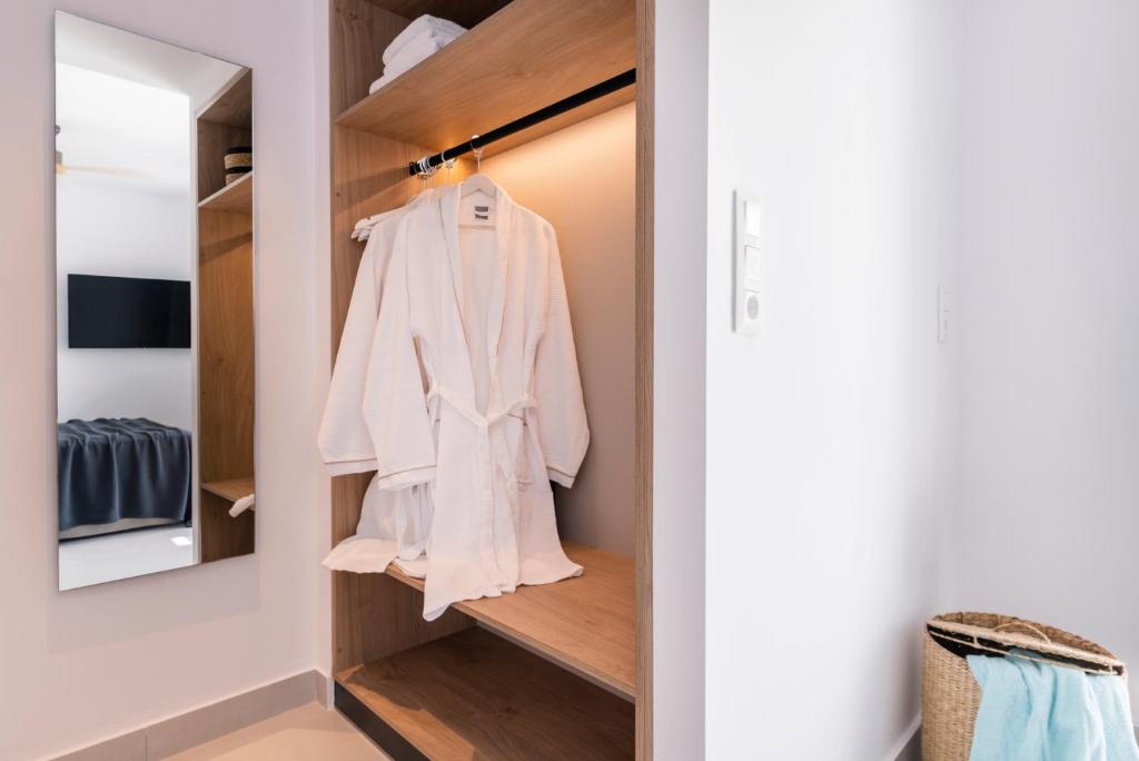 a walk in closet with a white robe hanging at Quartano Suites by Heliessa, Adults Only in Naousa