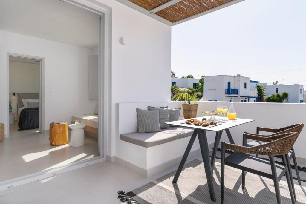 a dining room with a table and chairs on a balcony at Quartano Suites by Heliessa, Adults Only in Naousa