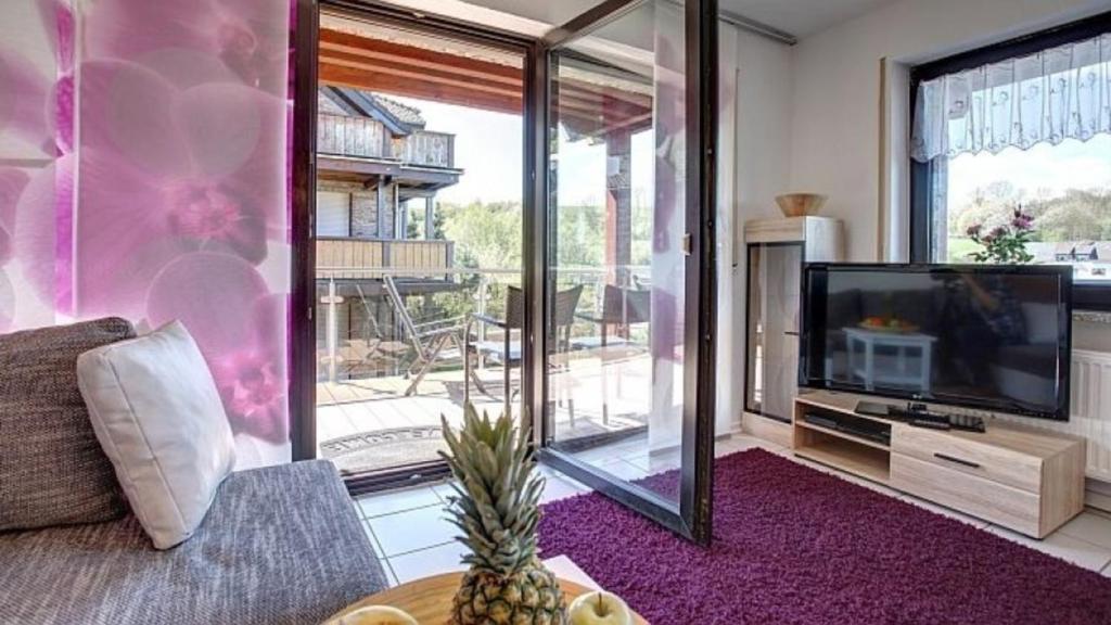 Una sala de estar con un sofá y un televisor. en Ferienwohnung Seeblick I, en Schalkenmehren