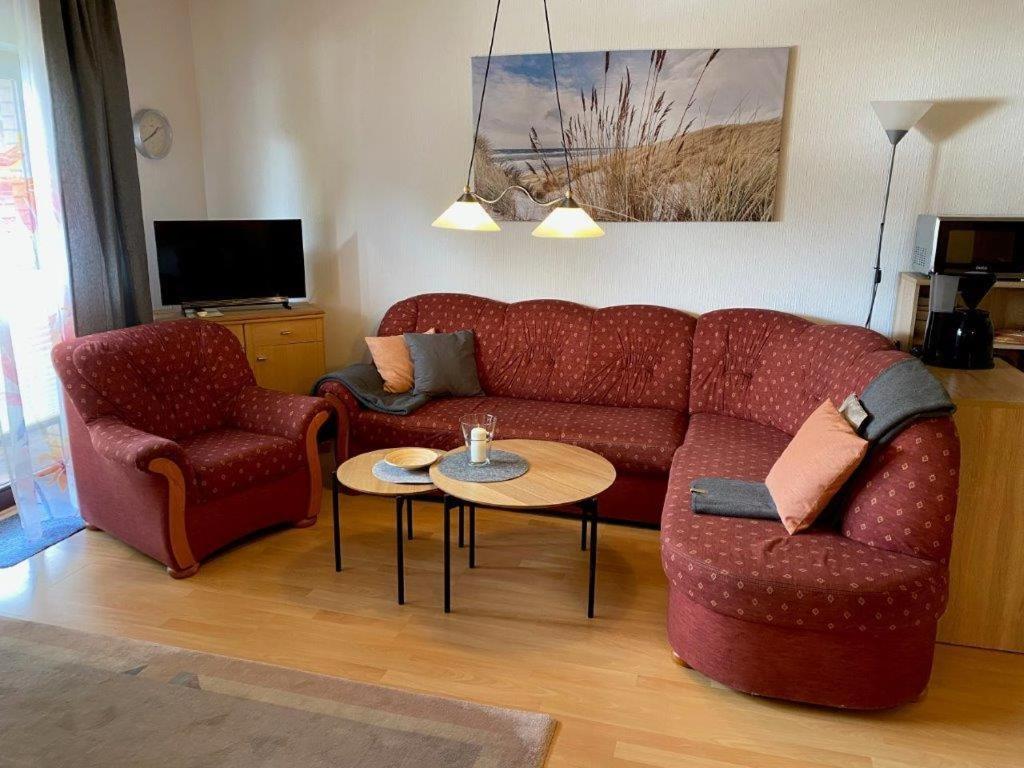 a living room with a red couch and a table at Ferienwohnung "Strandoase" in Burhave