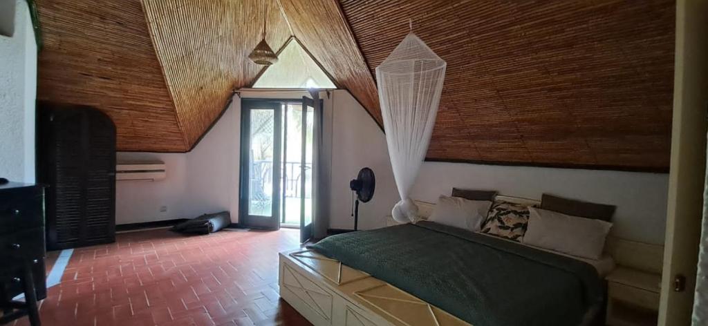 Sali PoulangにあるVILLA TABARA HOTEL LA TERANGA Saly Senegalの木製の天井のベッドルーム1室(ベッド1台付)