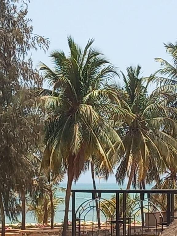 two palm trees on a beach with the ocean at VILLA TABARA HOTEL LA TERANGA Saly Senegal in Sali Poulang
