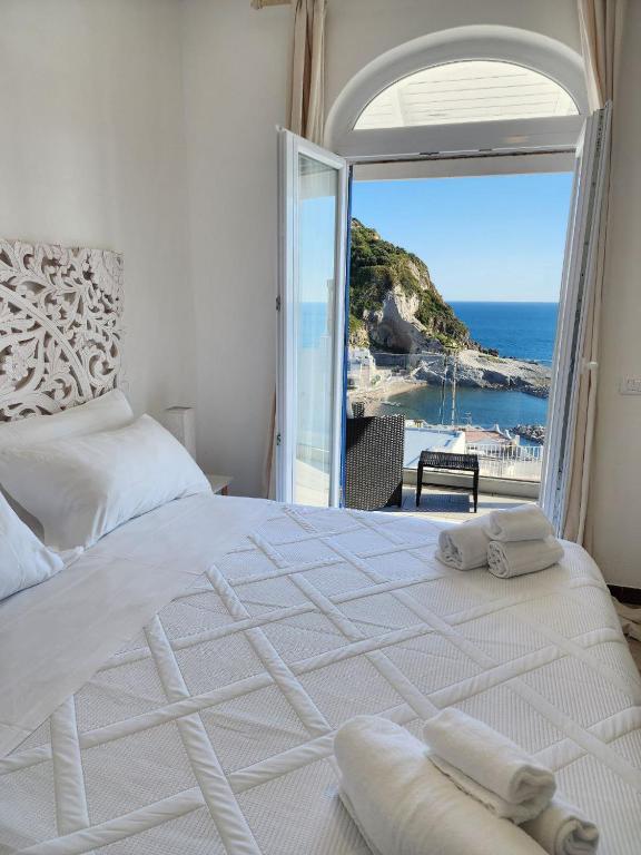 a bedroom with a white bed with a view of the ocean at Divina Seaside Suite Ischia in Sant'Angelo D'Ischia
