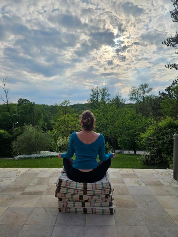 une femme assise sur une pile de briques en train de méditer dans l'établissement La petite galerie, à Bagneaux-sur-Loing