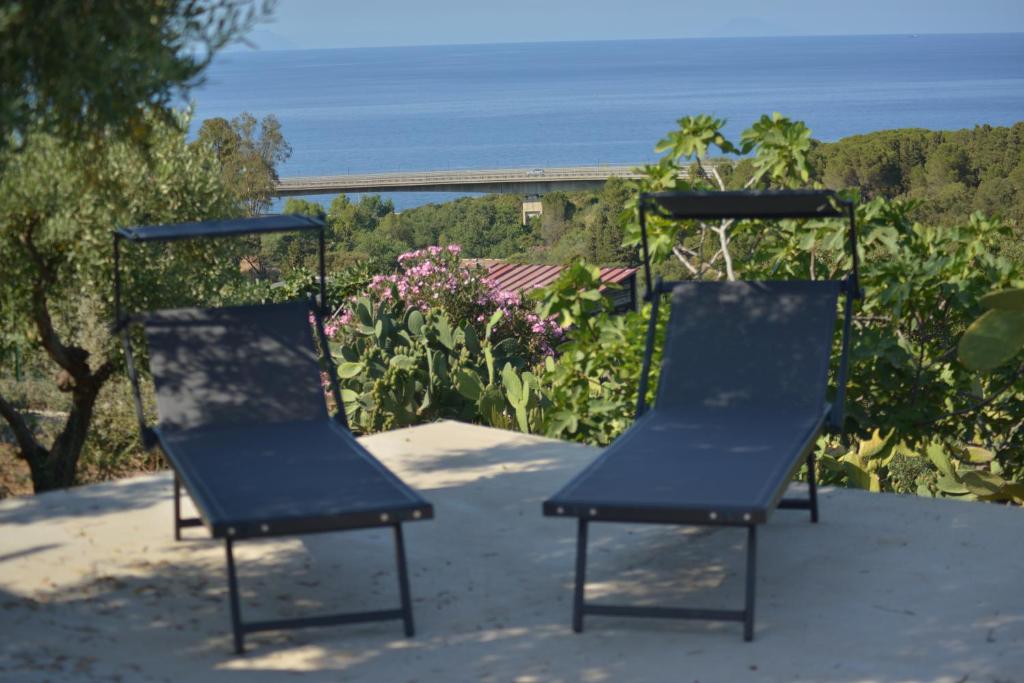 two chairs sitting on a patio with a view of the ocean at Donna Pulina Holidays in Pollina