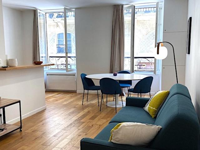un salon avec un canapé bleu et une table dans l'établissement Appartement Cosy Louvre Sentier, à Paris