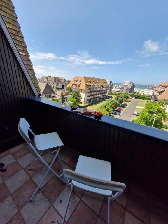 2 Stühle auf einem Balkon mit Stadtblick in der Unterkunft Villers vue sur mer in Villers-sur-Mer