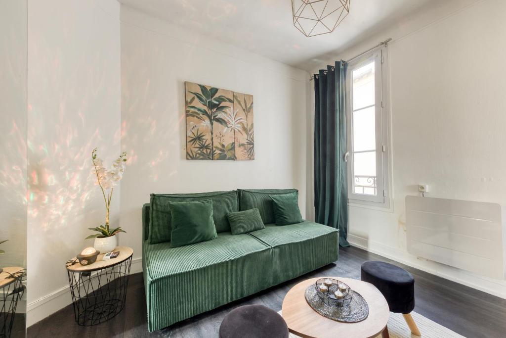 un salon avec un canapé vert et une table dans l'établissement Charmant appartement Porte de Paris - Vincennes, à Vincennes
