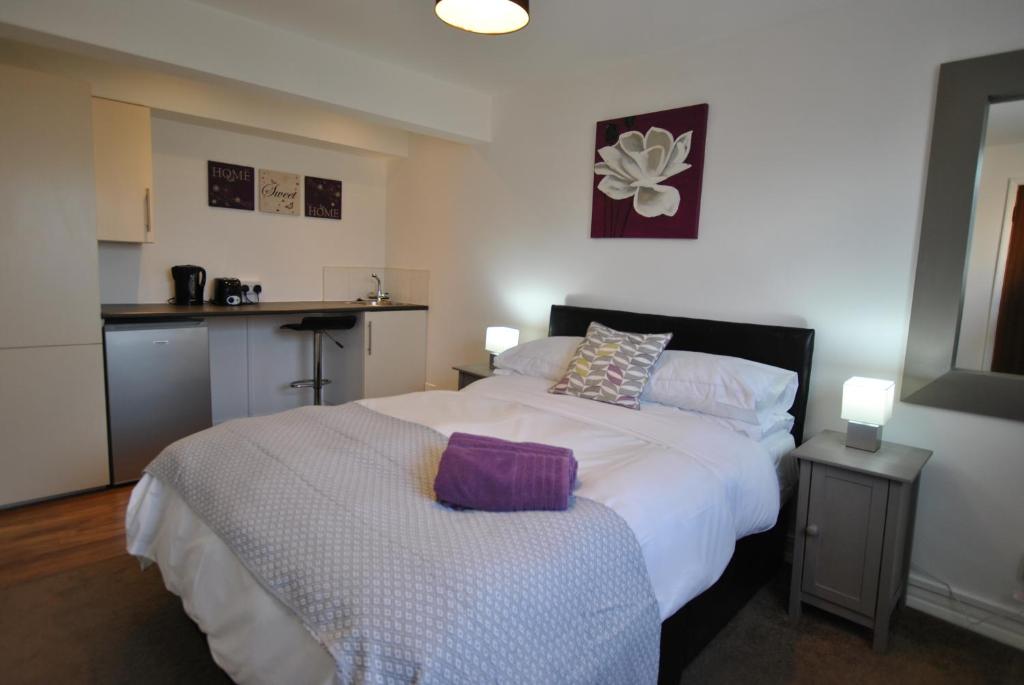 a bedroom with a large white bed and a kitchen at The Studios, Dedworth Road, by Accommodation Windsor in Windsor