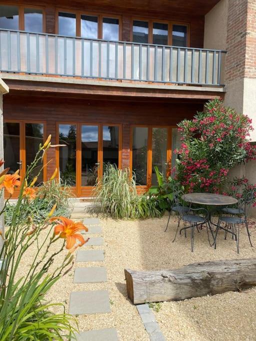 un patio avec une table et des chaises devant un bâtiment dans l'établissement Villa Pelanghi, maison Atypique en Drôme des collines, à Moras-en-Valloire