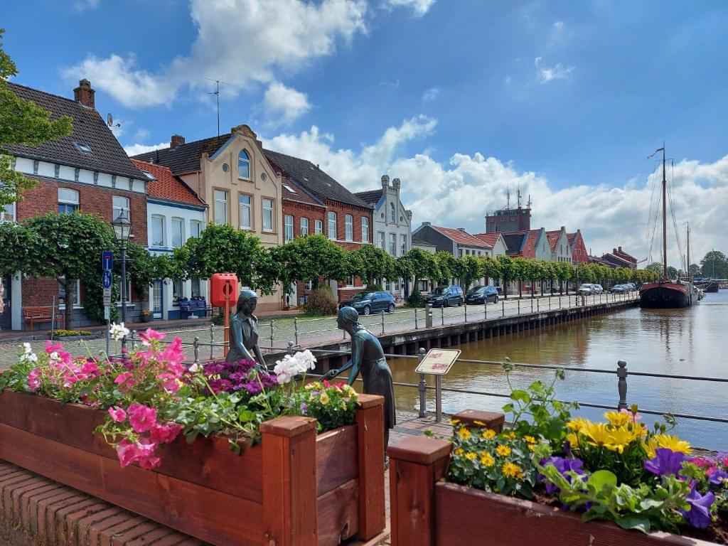 a group of statues next to a river with flowers at Ferienwohnung Rotbuche, 25517 in Weener