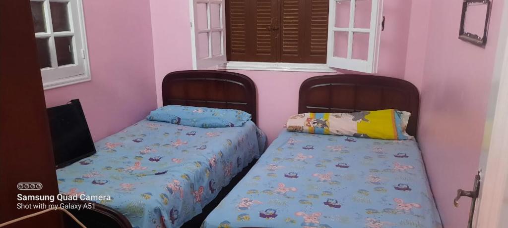 two beds in a room with two windows at Villa El kheer in `Ezbet el-Dabdûba