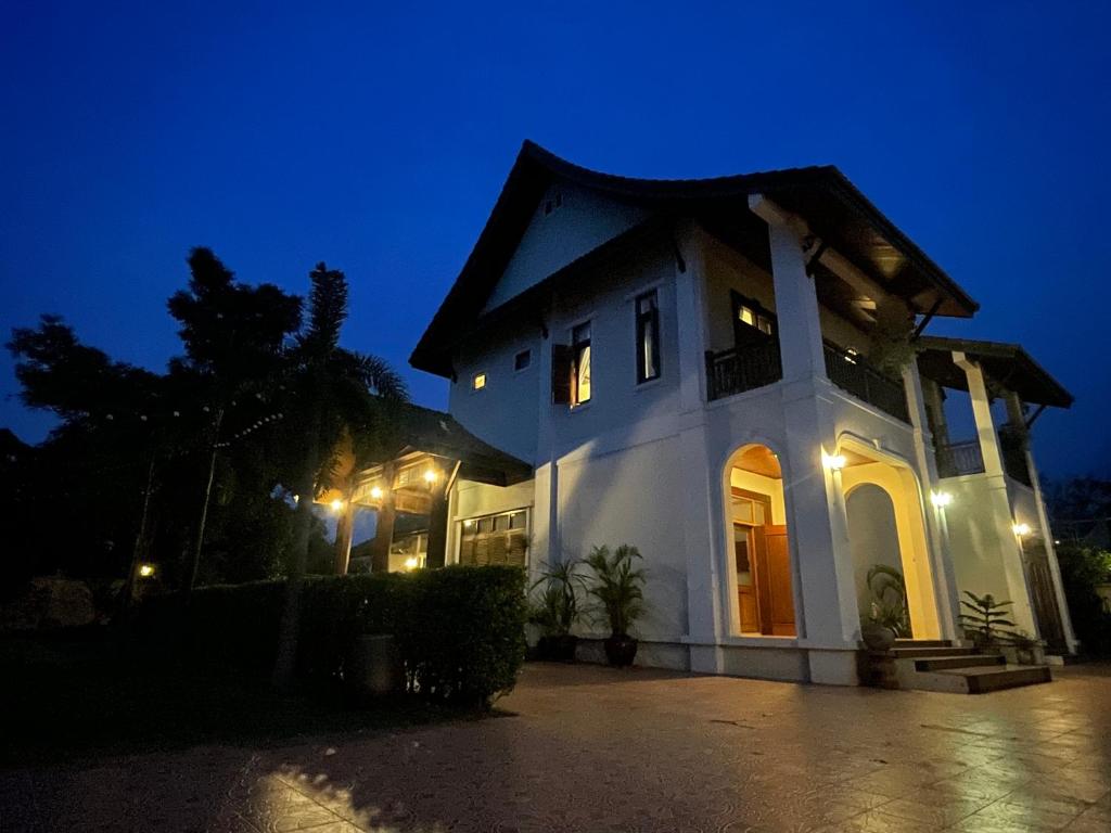 a white house at night with lights on at Owl House in Ban Kaoliao