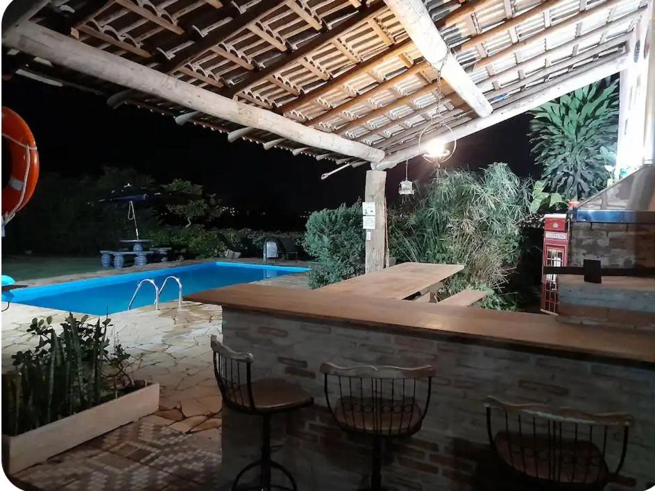 a patio with a bar and chairs next to a pool at Casa de Pedras na Montanha Stone House in Atibaia