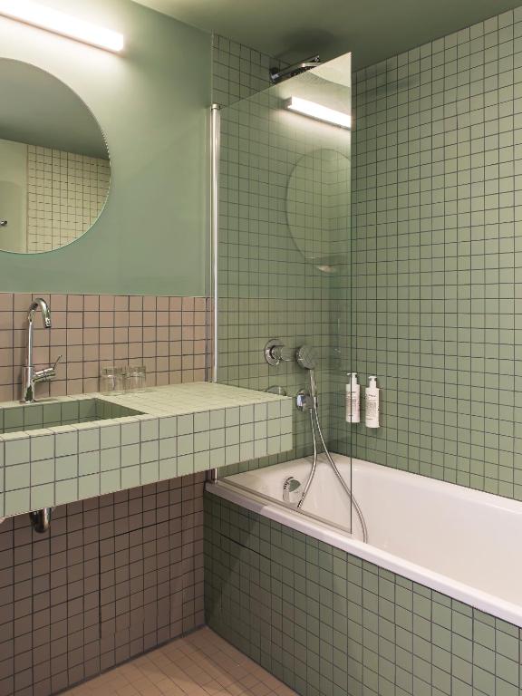 a bathroom with a shower and a tub and a sink at New Hotel Opéra in Paris