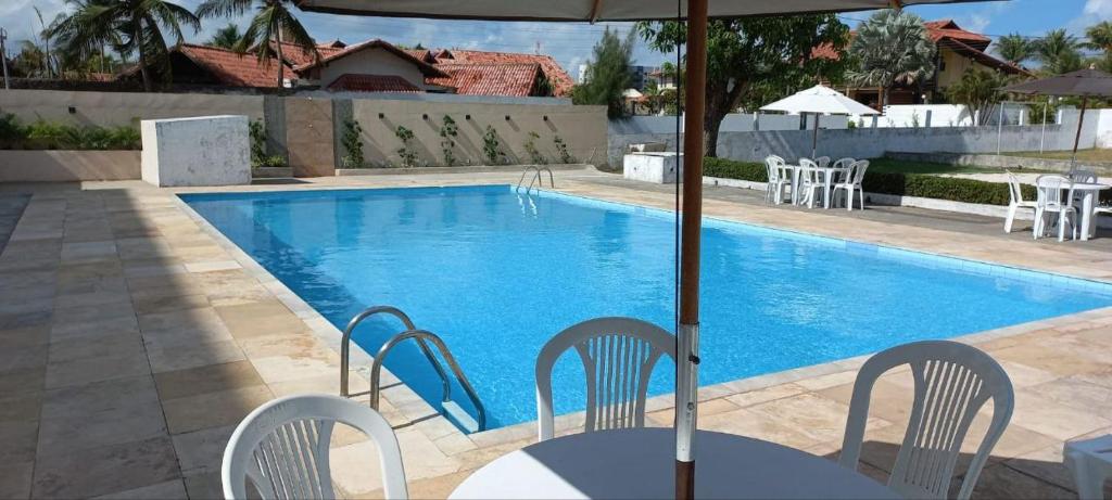 a swimming pool with chairs and a table and an umbrella at Hotel San Conrado in Salinópolis