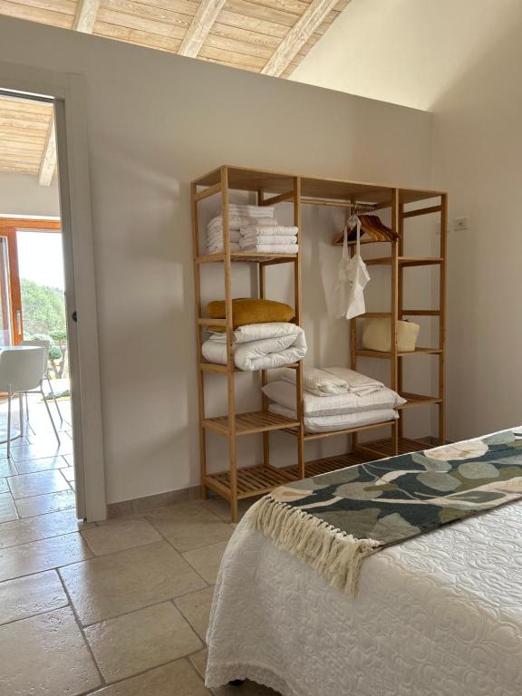 a room with a bed and a shelf with towels at Villa Case Vecchie in La Murta