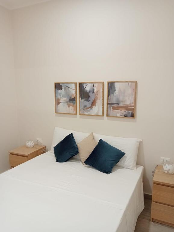 a bedroom with a white bed with four pictures on the wall at Butterfly Apartments in Palermo