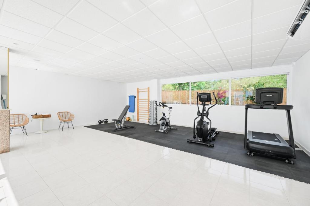 a gym with cardio equipment in a white room at Hotel Ankaa - Adults Only in Porto Cristo