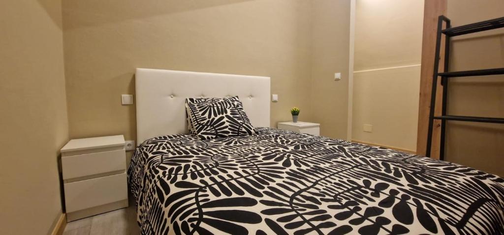 a bedroom with a bed with a black and white comforter at City Center Mindelo 37 in Mindelo