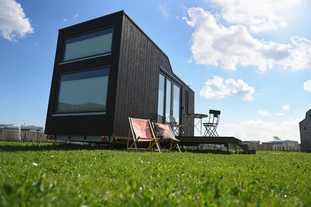a black house sitting on top of a lush green field at Tiny House Nature 10 Innenlage - Green Tiny Village Harlesiel in Carolinensiel