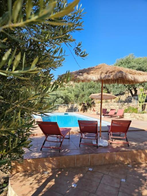 two chairs and an umbrella next to a swimming pool at Villa Finca el Carril in Vélez de Benaudalla