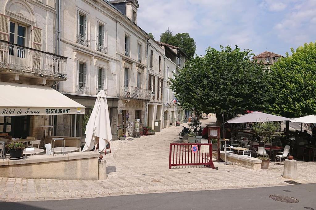 une rue avec un parasol, des tables et des bâtiments dans l'établissement Maison 2 chambres- grand jardin-WIFI - au cœur du village AUBETERRE -visites- conciergerie J&N, à Aubeterre-sur-Dronne