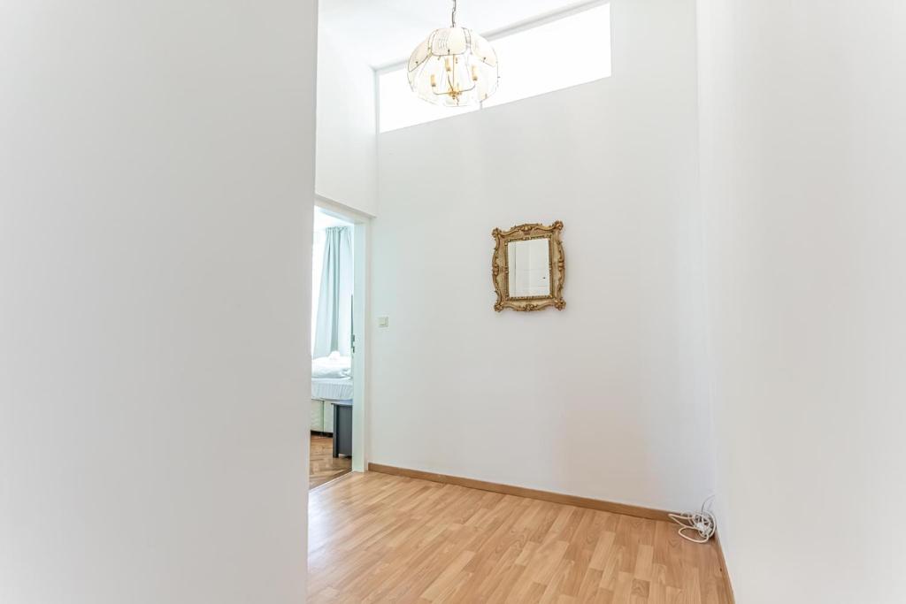 a room with a white wall and a chandelier at Convenient 3-BR Shared Apt, 15 Min to Landstraße Hub in Vienna