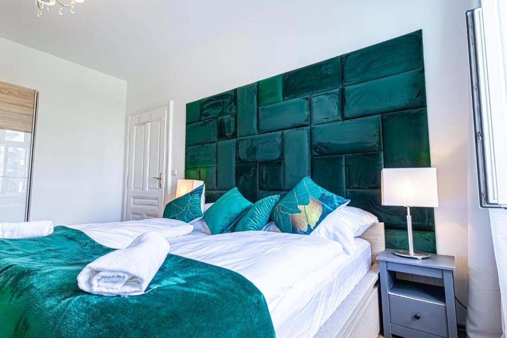 a bedroom with a large bed with a green headboard at Convenient 3-BR Shared Apt, 15 Min to Landstraße Hub in Vienna