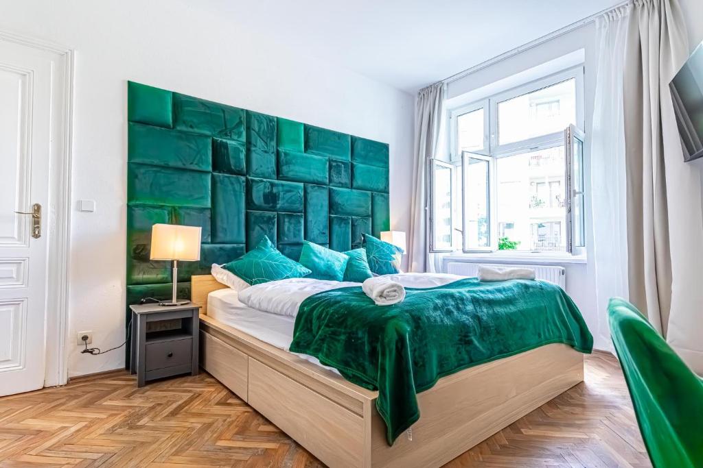 a bedroom with a large bed with a green headboard at Convenient 3-BR Shared Apt, 15 Min to Landstraße Hub in Vienna