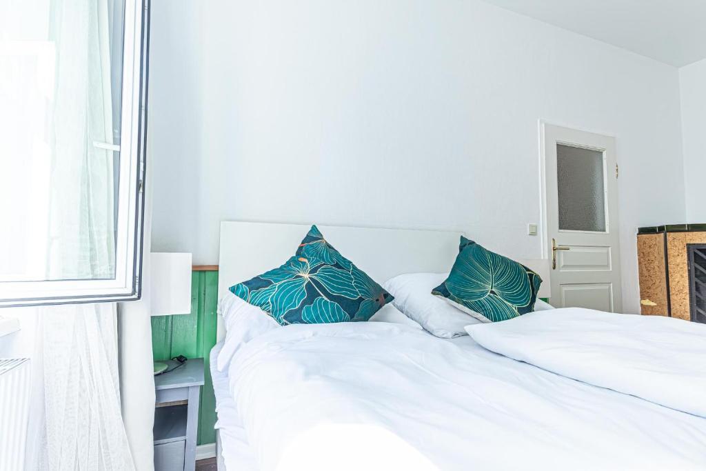 a white bed with two blue pillows on it at Convenient 3-BR Shared Apt, 15 Min to Landstraße Hub in Vienna