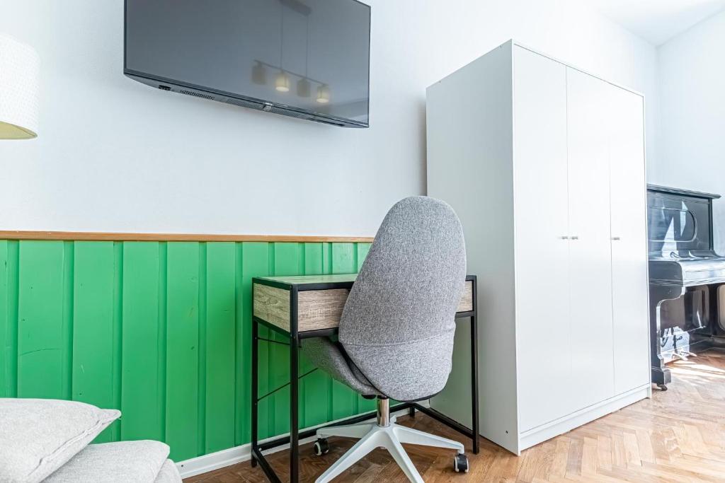 a desk and a chair in a room with a green wall at Convenient 3-BR Shared Apt, 15 Min to Landstraße Hub in Vienna