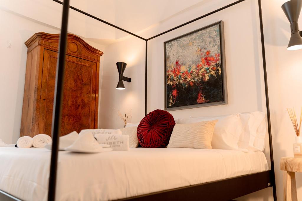 een slaapkamer met een wit bed met een rood kussen erop bij Lilibeth Luxury Suites - Ostuni in Ostuni